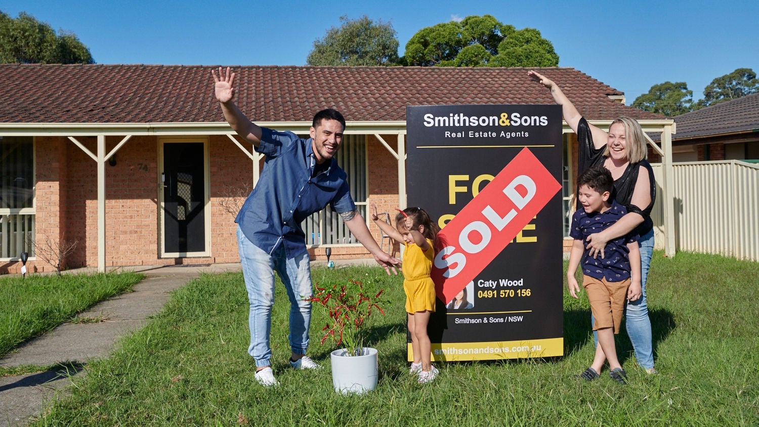 Happy family posing infont of new property bought at auction