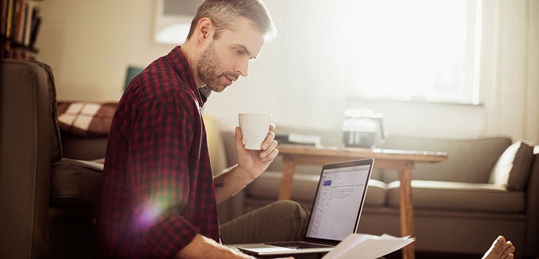 Photo of a man sitting on the floor and working on laptop