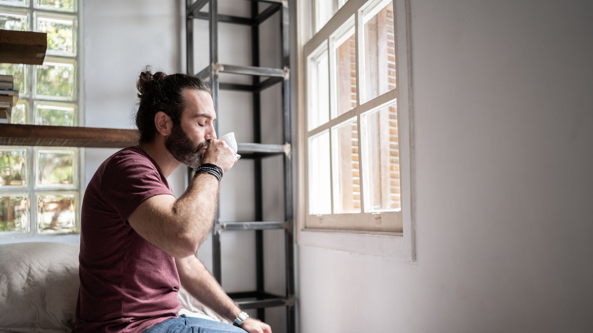 Man drinking coffee sitting in the bed at home