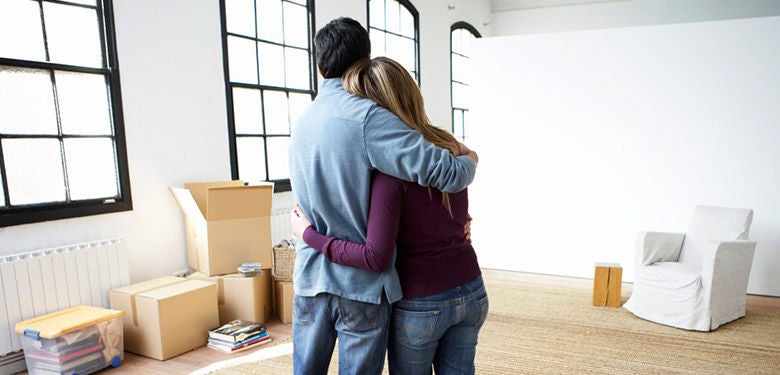 Couple moving house in empty room with boxes 